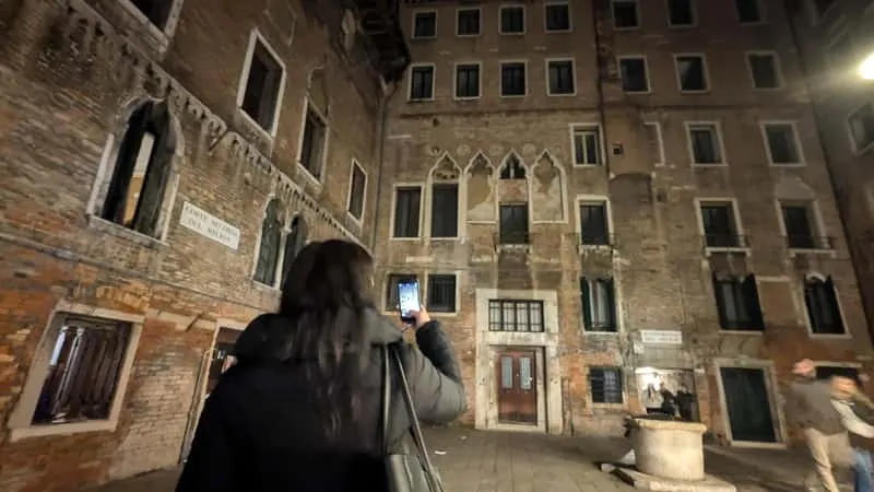 Small group on a ghost crimes and legends sunset walking tour in Venice Italy standing in a narrow lamplit alleyway at dusk